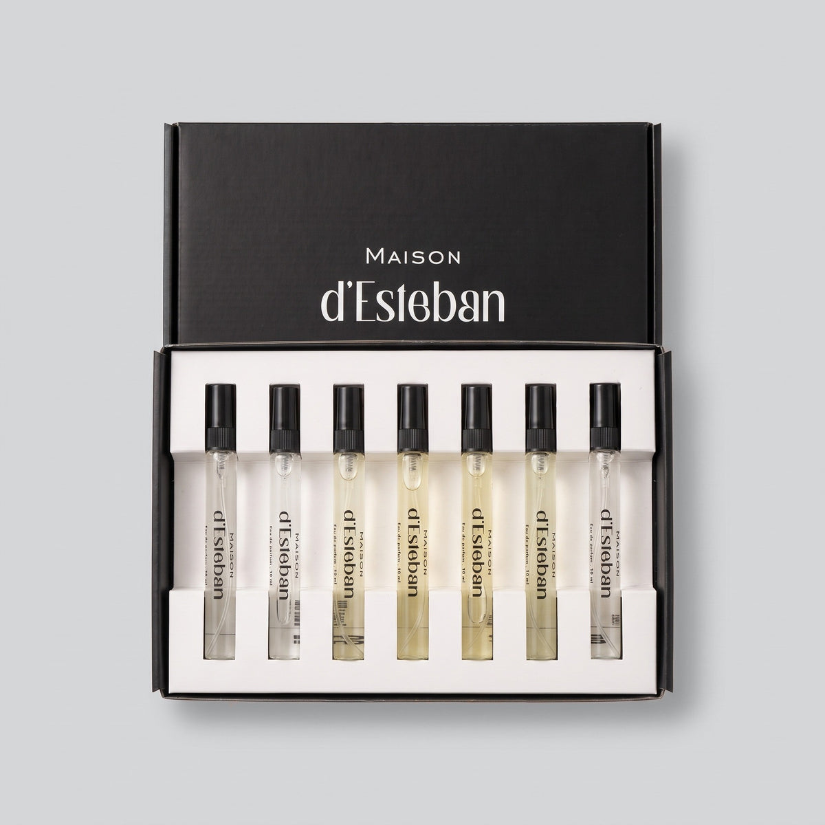 Set 7 parfumuri bărbătești Maison d'Esteban, cutia deschisă cu 7 fiole de 10 ml, pe fundal gri deschis