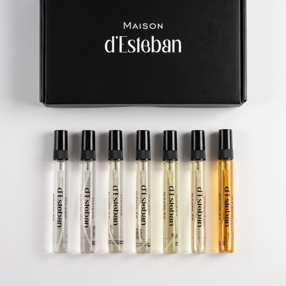 Cutia Maison d'Esteban și cele 7 fiole de 10 ml bărbătești așezate în rând, pe fundal alb