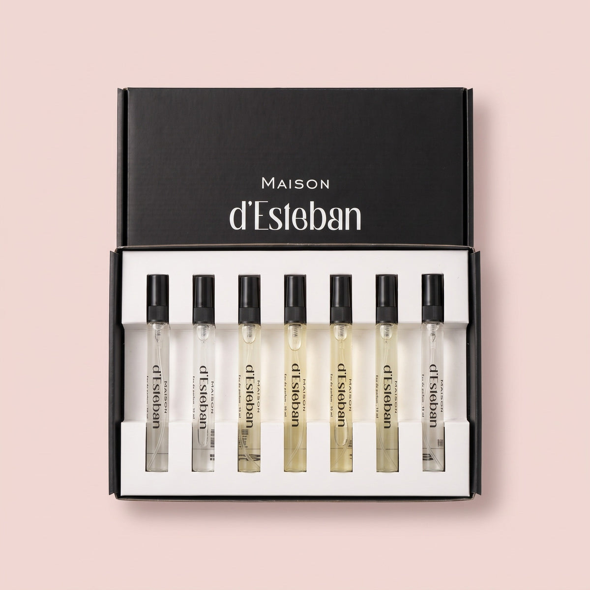 Set 7 parfumuri de damă Maison d'Esteban, cutia deschisă cu 7 fiole de 10 ml, pe fundal roz pal